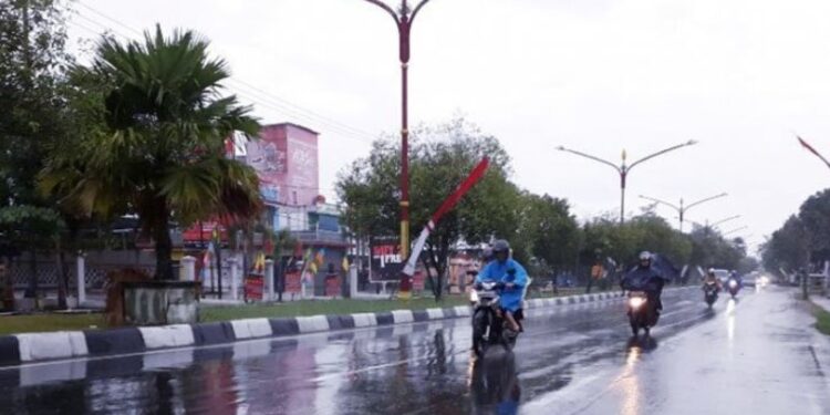 Dokumentasi. Warga melintas di Jalan RTA Milono diguyur hujan di Palangka Raya. (ANT)