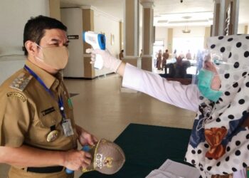 Petugas kesehatan memeriksa suhu tubuh Bupati Bartim Ampera AY Mebas saat memasuki Kantor Bupati Bartim di Tamiang Layang, Senin (5/10/2020). Kegiatan pemeriksaan suhu tubuh diharapkan menjadi contoh bagi SOPD di Bartim. (ANT)