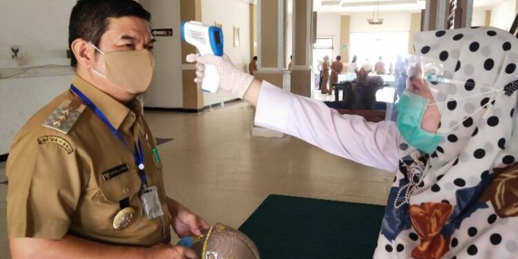 Petugas kesehatan memeriksa suhu tubuh Bupati Bartim Ampera AY Mebas saat memasuki Kantor Bupati Bartim di Tamiang Layang, Senin (5/10/2020). Kegiatan pemeriksaan suhu tubuh diharapkan menjadi contoh bagi SOPD di Bartim. (ANT)