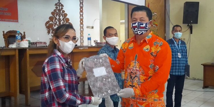 Komisioner KPU Gumas Yepta H Jina (kanan) menyerahkan DPT Pemilihan Gubernur dan Wakil Gubernur Kalteng 2020 kepada Kepala Bidang Kewaspadaan Nasional dan Penanganan Konflik pada Badan Kesbangpol Gumas Noni Waty, usai pelaksanaan pleno di Kuala Kurun, Jumat (16/10/2020). (MN-3)