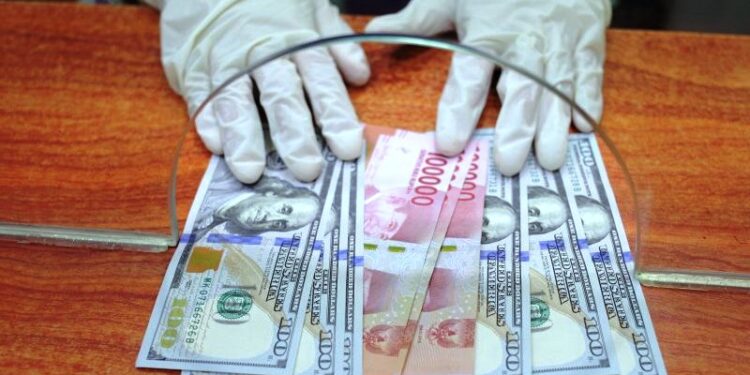 Petugas menunjukkan uang rupiah dan dolar AS di salah satu gerai penukaran mata uang asing di Jakarta, Kamis (2/4/2020). (ANTARA/RENO ESNIR)