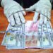Petugas menunjukkan uang rupiah dan dolar AS di salah satu gerai penukaran mata uang asing di Jakarta, Kamis (2/4/2020). (ANTARA/RENO ESNIR)