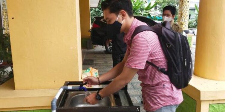 Ketika hendak bertamu, salah satu warga diwajibkan mencuci tangan di depan kantor DPRD Bartim di Tamiang Layang, Senin (26/10) lalu. (ANT)