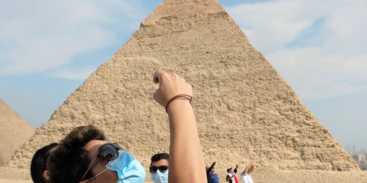 Wisatawan memakai masker pelindung mengikuti aturan yang diberlakukan akibat pandemi penyakit virus korona (COVID-19), terlihat di depan piramida Khafre atau "Chefren" di Giza, Mesir, Senin (9/11/2020). Foto diambil tanggal 9 November 2020. ANTARA FOTO/REUTERS/Amr Abdallah Dalsh/pras/cfo