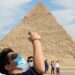 Wisatawan memakai masker pelindung mengikuti aturan yang diberlakukan akibat pandemi penyakit virus korona (COVID-19), terlihat di depan piramida Khafre atau "Chefren" di Giza, Mesir, Senin (9/11/2020). Foto diambil tanggal 9 November 2020. ANTARA FOTO/REUTERS/Amr Abdallah Dalsh/pras/cfo