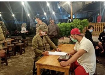 Petugas Satpol PP yang tergabung dalam Satgas COVID-19 Kabupaten Kapuas, memberikan edukasi dan sosialisasi tetang protokol kesehatan kepada salah satu pengunjung kafe di Kota Kuala Kapuas, Selasa, (22/12) malam. (ANT/IST)