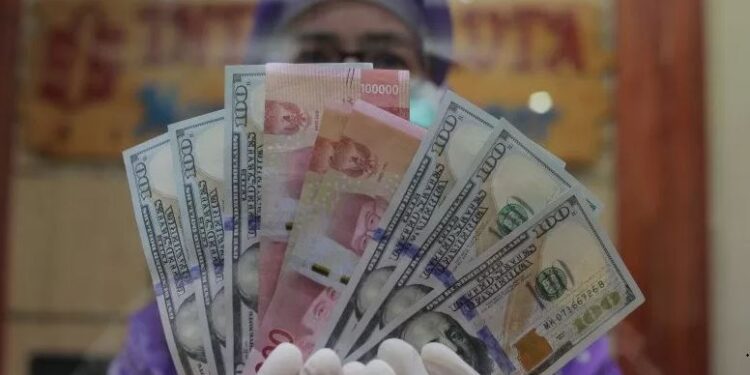 Petugas menunjukkan uang rupiah dan dolar AS di salah satu gerai penukaran mata uang asing di Jakarta. ANTARA FOTO/Reno Esnir/foc (ANTARA/RENO ESNIR)