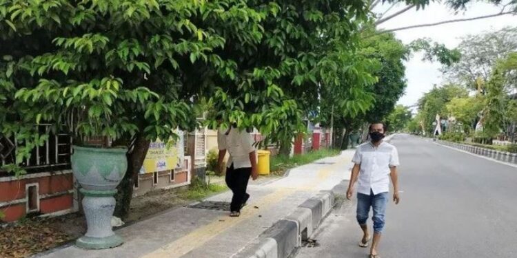 Pejalan kaki terpaksa berjalan di trotoar sambil menunduk, ada pula yang memilih berjalan di aspal jalan karena trotoar terhalang rimbunnya dahan pohon, Jumat (29/1/2021). (ANT)