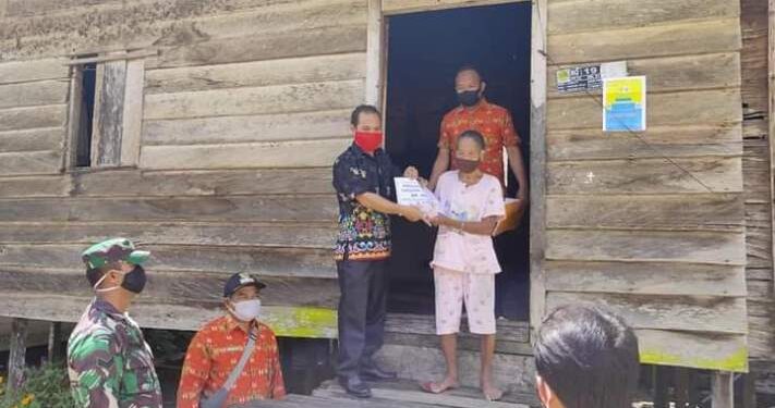 Foto Dokumentasi - Kasi Penataan Administrasi Desa DPMD Gumas Simon (batik hitam), menyalurkan BLT DD di Desa Jangkit, Kecamatan Rungan Hulu pada 2020 lalu. (HO-DPMD Gumas)