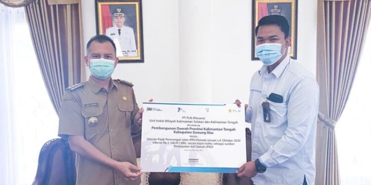 Plt Manajer PLN ULP Kuala Kurun, Agung Darmawan (kanan) menyerahkan setoran PPJ Januari – Oktober 2020 kepada Bupati Gumas, Jaya S Monong, di Kuala Kurun, Selasa (5/1/2021). (Foto : Protokol dan Perjalanan Setda Gumas)