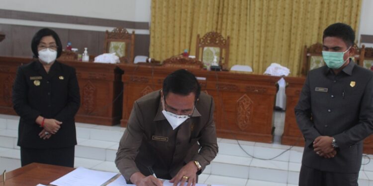 Ketua DPRD Gumas Akerman Sahidar disaksikan Wakil Ketua I Binartha, Wakil Bupati Efrensia L.P Umbing menandatangani persetujuan bersama terhadap dua raperda, saat rapat paripurna di Kuala Kurun, Rabu (24/3/2021). (Foto : Setwan Gumas)