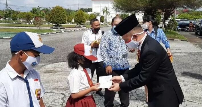 Bupati Gumas Jaya S Monong menyalurkan beasiswa Gunung Mas Pintar secara simbolis kepada peserta didik SD, usai upacara Peringatan Hari Pendidikan Nasional, di Kuala Kurun, Senin (3/5/2021). (ANT/IST)
