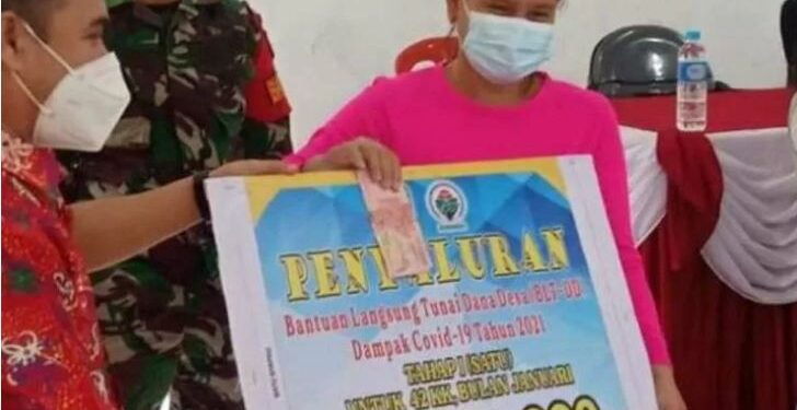 Kasi Penataan Administrasi Desa pada DPMD Kabupaten Gumas Simon (kiri) menyalurkan BLT DD Januari 2021 secara simbolis kepada KPM di Desa Batu Nyapau, Kecamatan Tewah, Sabtu (1/5/2021). (ANT/IST)