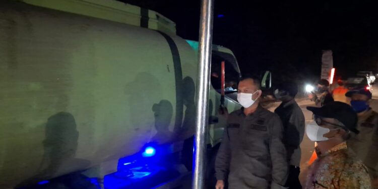 Bupati Gumas Jaya S Monong (kiri) didampingi Staf ahli Gubernur Herson B Aden dan lainnya memantau truk angkutan yang melintas di portal atau alat pembatas tinggi dan lebar kendaraan, di ruas jalan Palangka Raya-Kuala Kurun, tepatnya di Desa Sepang Kota, Kecamatan Sepang, Kabupaten Gumas, Jumat malam (23/7/2021). (IST)