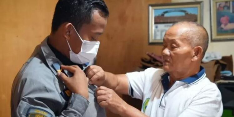 Juminto, ayah dari Serda Dodi Wardiono memakaikan seragam prajurit TNI AD sang anak sebelum Dodi berangkat kembali bertugas. (ANT/IST)