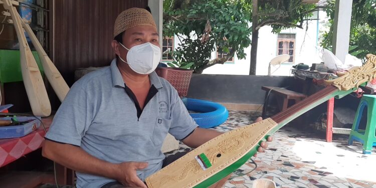 Harmuda menunjukkan kecapi ukiran timbul, di kediamannya di Kelurahan Tampang Tumbang Anjir, Kecamatan Kurun, Kabupaten Gunung Mas, Sabtu (7/8/2021). (Foto : MASAPNEWS/GCM)