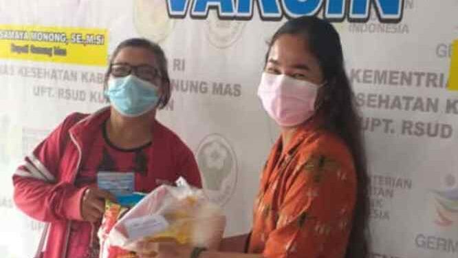 Ketua DPK PPNI RSUD Kuala Kurun Sriwani Yupita Rina (kanan) menyerahkan undian doorprize kepada masyarakat yang beruntung, saat pelaksanaan vaksinasi di RSUD Kuala Kurun, Kamis (5/8/2021). (Foto : PPNI Kabupaten Gumas)