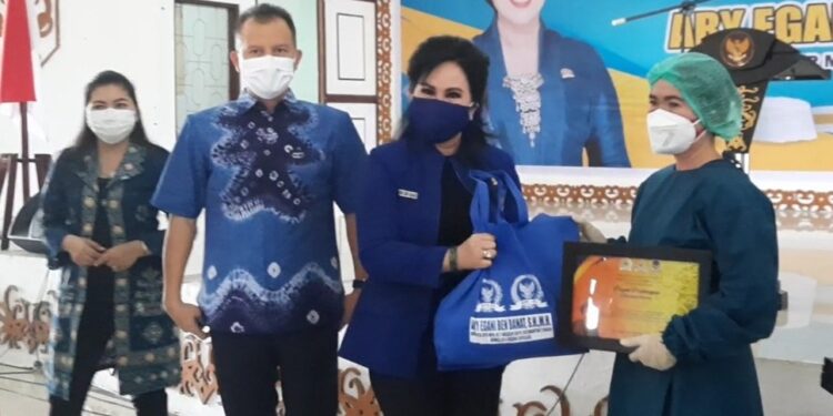 Anggota DPR RI Ary Egahni didampingi Bupati Gumas Jaya S Monong dan Ketua TP PKK Kabupaten Gumas Mimie Mariatie Jaya S Monong menyerahkan piagam penghargaan dan lainnya kepada tenaga kesehatan, yang diterima secara simbolis oleh Kepala Puskesmas Tampang Tumbang Anjir Nevie Ervina, saat pelaksanaan vaksinasi massal di GPU Damang Batu, Sabtu (14/8/2021). (GCM/MN-3)