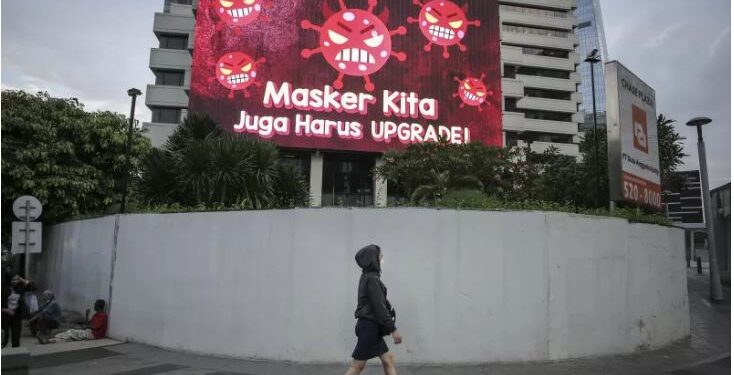 Warga berjalan di depan videotron mengenai protokol kesehatan di Jalan Jenderal Sudirman, Jakarta, Senin (13/9/2021). Pemerintah memutuskan terus melanjutkan PPKM tingkat II-IV di Pulau Jawa-Pulau Bali hingga 20 September 2021 untuk menekan penyebaran Covid-19. ANT/IST