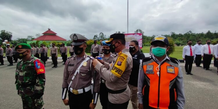 Kapolres Gumas AKBP Irwansah menyematkan pita sebagai tanda dimulainya operasi patuh telabang tahun 2021 di halaman mapolres setempat, Senin (20/9/2021). (Foto : Polres Gumas)