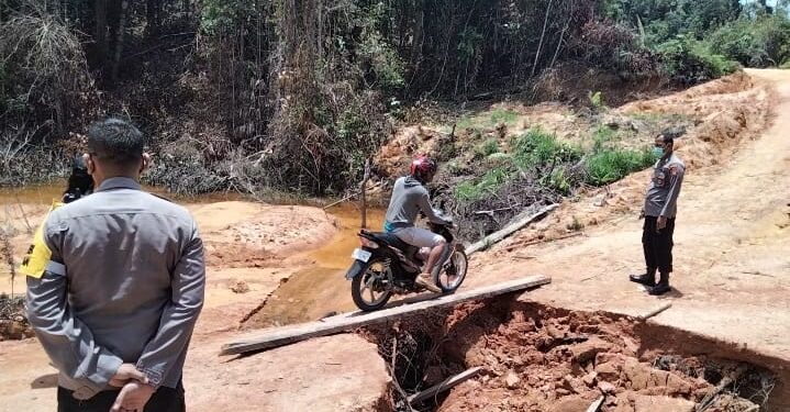Polisi mengawasi pengendara roda dua yang melintas ruas jalan Kuala Kurun-Linau yang mengalami longsor, Selasa (14/9/2021). (Foto : Polsek Rungan)