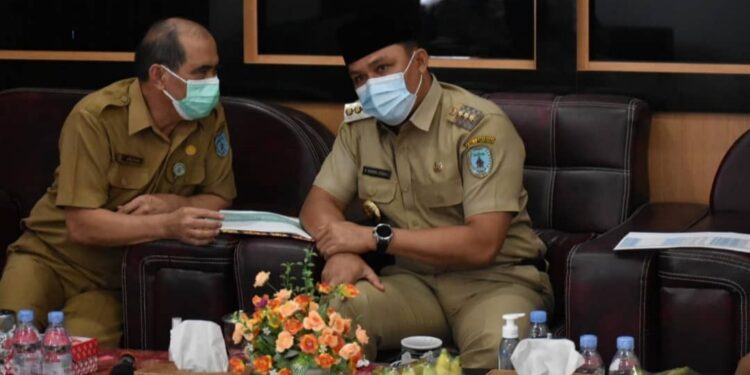 Bupati Lamandau H Hendra Lesmana sedang berdiskusi dengan Kepala Bappeda Drs Abisua saat rapat evaluasi penyerapan anggaran secara virtual diaula Bappeda setempat, kemarin.