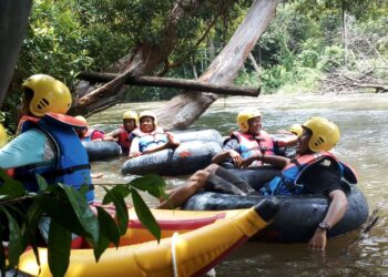 Para wisata arung jeram saat menikmati keindahan sungai dan hutan tropisnya masih hijau.