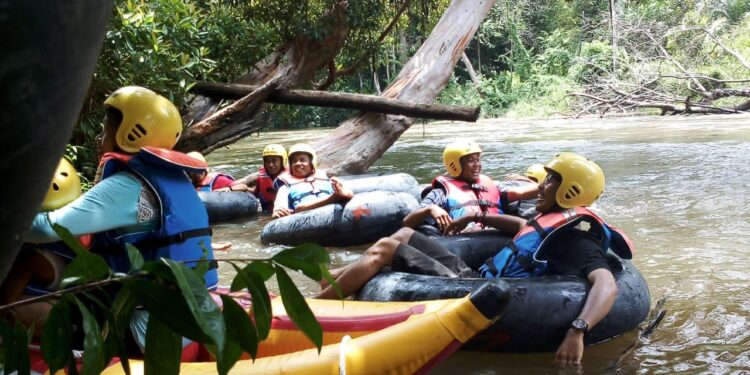 Para wisata arung jeram saat menikmati keindahan sungai dan hutan tropisnya masih hijau.