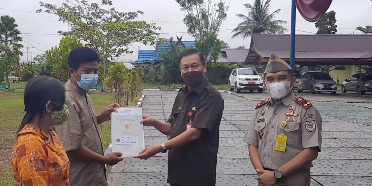 ekda Gumas Yansiterson (kanan kedua) didampingi Kepala BPN Gumas Ferdinan Adinoto (kanan) menyerahkan sertifikat tanah program PTSL secara simbolis, di halaman kantor BPN setempat, Jumat (24/9/2021).