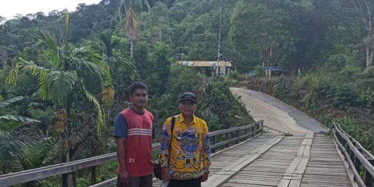 Camat Damang Batu, Damai (batik kuning) didampingi Kades Tumbang Anoi saat meninjau infrastruktur jembatan yang dibangun dengan menggunakan DD, baru-baru ini. (Foto : Dokumentasi pribadi)