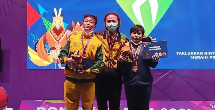 Lifter Sri Hartati berpose di tengah podium kemenangan lomba angkat berat 57kg putri PON XX Papua yang diselenggarakan di Auditorium Universitas Cenderawasih Jayapura, Papua, Selasa (12/10/2021). (ANT/IST).