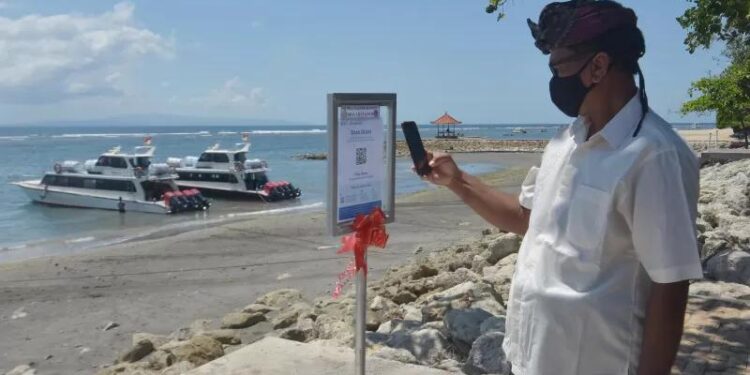 Ilustrasi warga memindai kode batang sertifikat vaksin COVID-19 menggunakan aplikasi PeduliLindungi saat berkunjung di Pantai Sanur, Denpasar, Bali, Kamis (30/9/2021). Penerapan aplikasi PeduliLindungi di objek wisata yang dicanangkan sebagai kawasan zona hijau bebas COVID-19 tersebut untuk menjaga kesehatan masyarakat yang akan berdampak positif bagi pemulihan ekonomi di tempat pariwisata Sanur serta sebagai upaya menekan penyebaran COVID-19. (MASAPNEWS/ANT/Nyoman Hendra Wibowo)