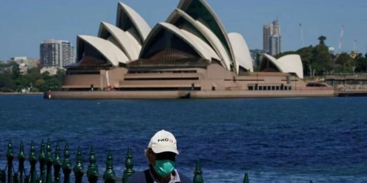Seorang warga berjalan di tepi pelabuhan di seberang Sydney Opera House selama penguncian COVID-19 di Sydney, Australia, Rabu (6/10/2021). (MASAPNEWS/ANT/Reuters)