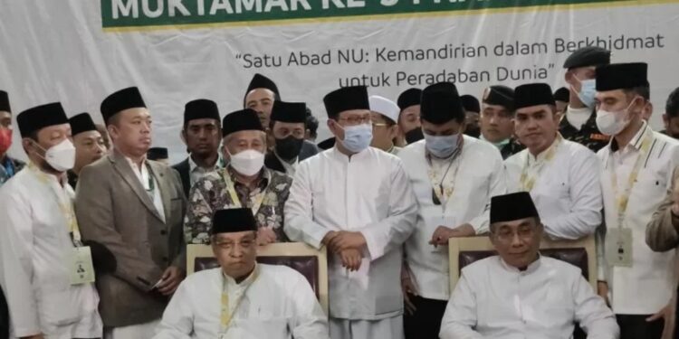 K.H Said Aqil Siradj (kir putih) dan Gus Yahya (putih kanan) duduk bersama usai penghitungan suara Ketua Umum (Ketum) PBNU di Gedung Serba Guna (GSG) Unila. Jumat, (24/12/2021). (MASAPNEWS/ANT)