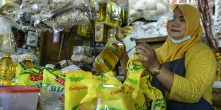 Seorang pedagang menunjukkan minyak goreng kemasan dagangannya di Pasar Malaka, Rorotan, Jakarta, Senin (3/1/2022). (MASAPNEWS/ANT)