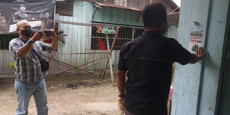 Sekretaris PWI Kabupaten Gumas Arham Said (kemeja hitam) sedang menempelkan stiker Napza di rumah warga di Kuala Kurun, Kamis (10/2/2022). (IST)