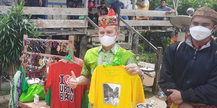 Bupati Gumas Jaya S Monong (batik hijau muda) melihat berbagai cendera mata yang dijual oleh Sanggar Seni dan Budaya Segah Batuah Tewah usai meresmikan Huma Adat Hamputan Stefanus Singarasa Tunda di Desa Batu Nyiwuh, Kecamatan Tewah, Sabtu (5/3/2022). (MASAPNEWS/GCM)