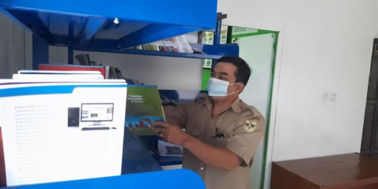 Kades Tewang Pajangan Mulyadi menunjukkan ratusan buku yang merupakan bantuan dari Perpusnas dan saat ini sudah tersedia di perpustakaan desa setempat, Senin (21/3/2022). (MASAPNEWS/GCM)