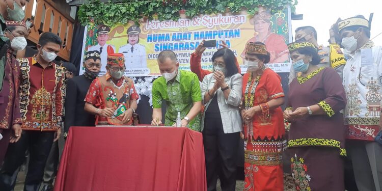 Bupati Gumas Jaya S Monong disaksikan Wabup Efrensia L.P Umbing, Wakil Ketua I DPRD Gumas Binartha, dan Hamputan Stefanus Singarasa Tunda menandatangani prasasti Rumah Adat Hamputan Stefanus Singarasa Tunda di Desa Batu Nyiwuh Kecamatan Tewah, Sabtu (5/3/2022). (MASAPNEWS/GCM)