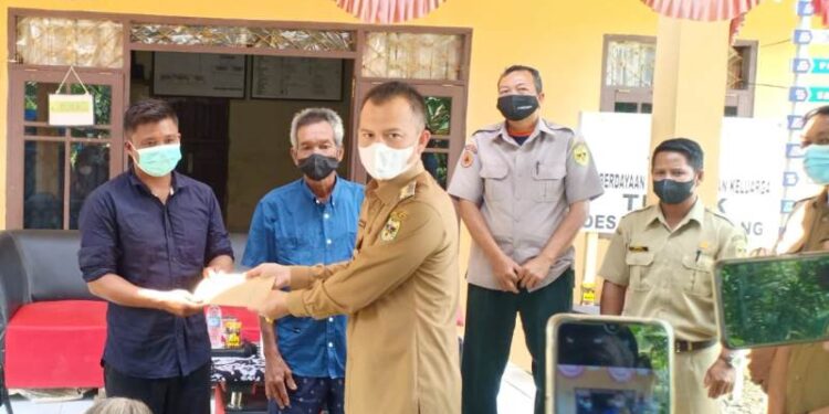 Bupati Gumas Jaya S Monong didampingi Kepala Pelaksana BPBD Gumas Champili, Kades Penda Pilang Jhonedie dan lainnya saat menyalurkan bantuan dana kepada warga yang terkena musibah kebakaran rumah, di Desa Penda Pilang Kecamatan Kurun, Selasa (22/2/2022). (Foto : BPBD Kabupaten Gumas)