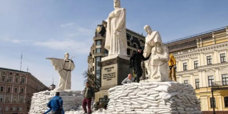 Relawan menutupi monumen Putri Olga, Rasul Andrew, Santo Cyril dan Methodius dengan kantong pasir untuk melindunginya dari kerusakaan saat invasi Rusia di Ukraina berlanjut, di Kiev, Ukraina, 28 Maret 2022. (MASAPNEWS/ANT/Reuters)