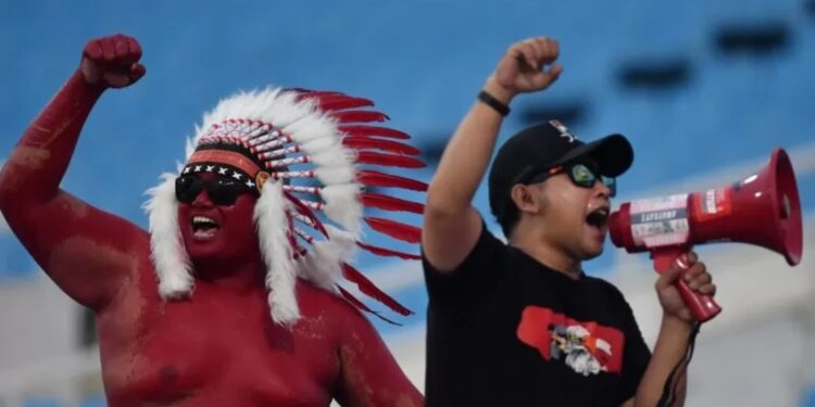 Dua suporter Indonesia memberikan dukungan kepada tim nasional U-23 Indonesia saat bertanding melawan tim nasional Thailand U-23, di Stadion Nasional My Dinh, Hanoi, Vietnam, Jumat (22/3/2019). Tim nasional Thailand U-23 mengalahkan tim nasional U-23 Indonesia dengan skor 4-0. (MASAPNEWS/ANT)