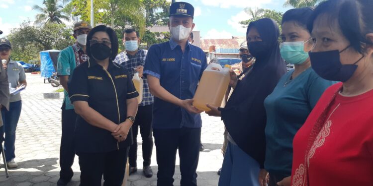 Bupati Gumas Jaya Samaya Monong didampingi Wabup Efrensia LP Umbing saat menyerahkan minyak goreng curah 5 liter kepada warga setempat di Kuala Kurun, Sabtu (23/4/2022). (MASAPNEWS/HY)