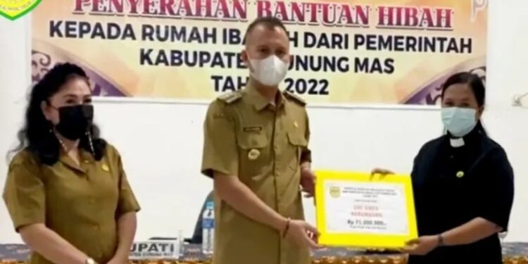 Tangkapan layar – Bupati Gunung Mas Jaya S Monong didampingi Kabag Administrasi Kesejahteraan Rakyat dan Kemasyarakatan di Setda Gunung Mas Vonny Rita (kiri) menyalurkan bantuan dana hibah rumah ibadah di Kecamatan Rungan Barat, Selasa (19/4/2022), pada akun Facebook @Sobat Muda Jaya. (MASAPNEWS/ANT)