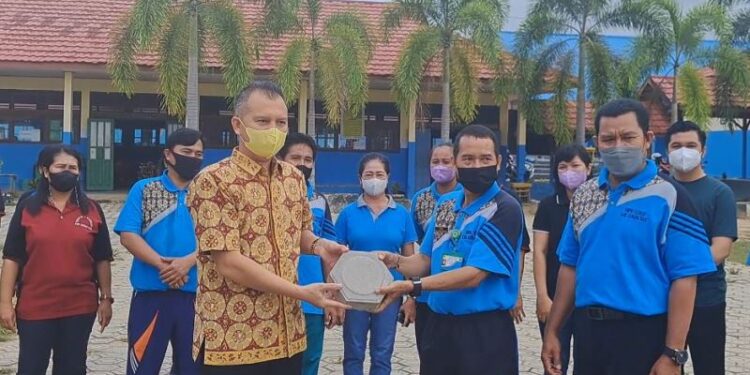 Bupati Gunung Mas Jaya S Monong (kemeja batik) menyalurkan bantuan paving block secara simbolis kepada Kepala SMPN 1 Kurun Yono di halaman sekolah, Jumat (29/7/2022). (MASAPNEWS/GCM)