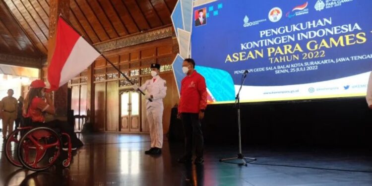 Atlet para angkat berat National Paralympic Committees (NPC) Indonesia Ni Nengah Widyasih (kiri) mencium bendera merah putih dengan disaksikan Menpora Zainudin Amali (kanan) saat acara Pengukuhan dan Pelepasan Kontingen Indonesia untuk ASEAN Para Games XI 2022 di Balai Kota Solo, Jawa Tengah, Senin (25/7/2022). Tim NPC Indonesia menargetkan bisa menjadi juara umum di ASEAN Para Games Solo 2022 dengan minimal memperoleh 104 medali emas. (MASAPNEWS/ANT)