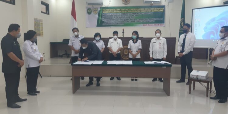 Ketua PN Kuala Kurun Bukti Firmansyah saat menandatangani nota kesepahaman di ruang sidang utama PN setempat yang disaksikan Wabup Gumas Efrensia LP Umbing dan ketua Pengadilan Tinggi Palangkaraya H Zainuddin, Rabu (20/7/2022). (MASAPNEWS/HY)