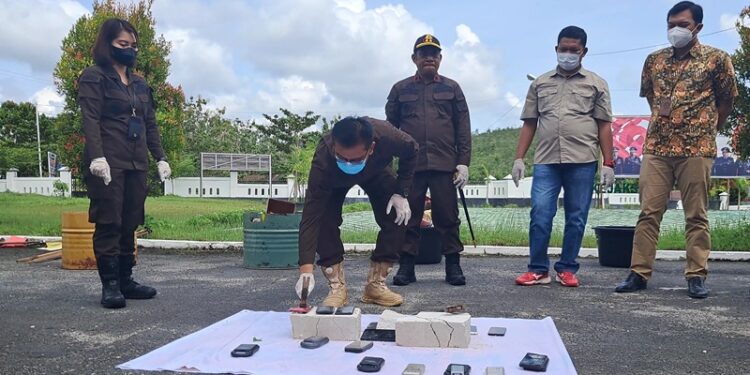 Kajari Gunung Mas Nixon Nikolaus Nila (mengenakan topi) dan lainnya menyaksikan pemusnahan barang bukti yakni telepon seluler, di halaman kantor Kejari setempat, Kamis (15/9/2022). (MASAPNEWS/HY)