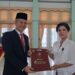 Bupati Gumas, Jaya S Monong (kiri) menyampaikan penghargaan Satyalancana Karya Satya dari Presiden RI kepada Kepala SDN 1 Kuala Kurun, Desmilawati, di GPU Damang Batu Kuala Kurun, Jumat (28/10/2022). (IST)