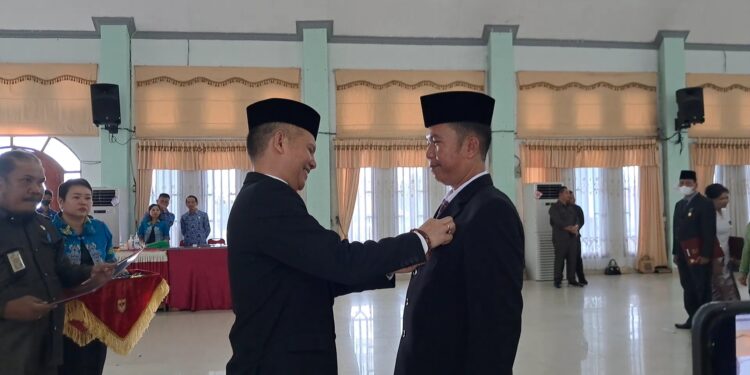 Bupati Gumas, Jaya S Monong (kiri) menyematkan penghargaan Satyalancana Karya Satya dari Presiden RI kepada Kepala SDN 3 Kuala Kurun, Belie, di GPU Damang Batu Kuala Kurun, Jumat (28/10/2022). (IST)